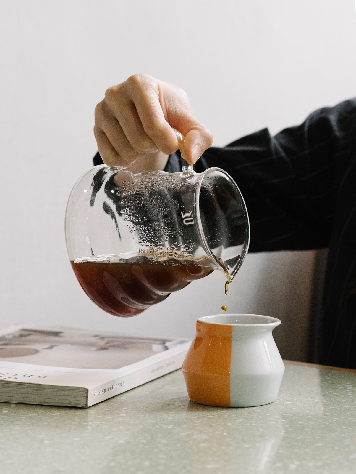 jemand gießt Kaffee aus Glaskanne in kleine orangene 2-waycup Tasse