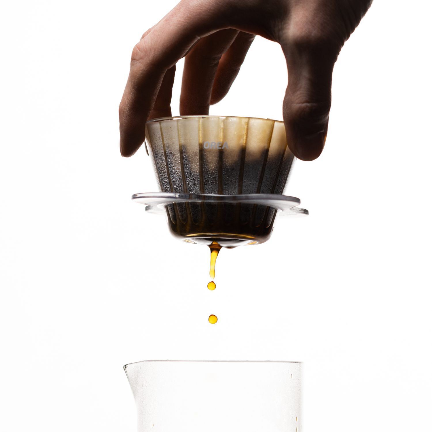 Hand hält durchsichtigen Dripper mit Filterpapier und Kaffee gefüllt