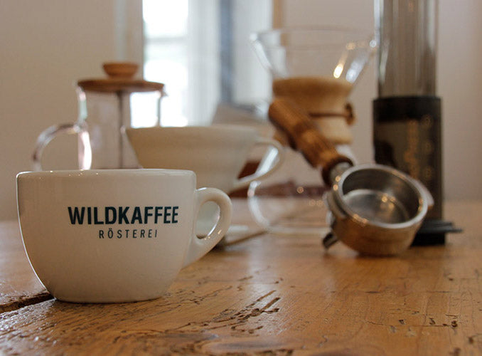 Wildkaffeetasse im Vordergrund, hinten ein Siebträger, eine French Press eine Chemex und mehr