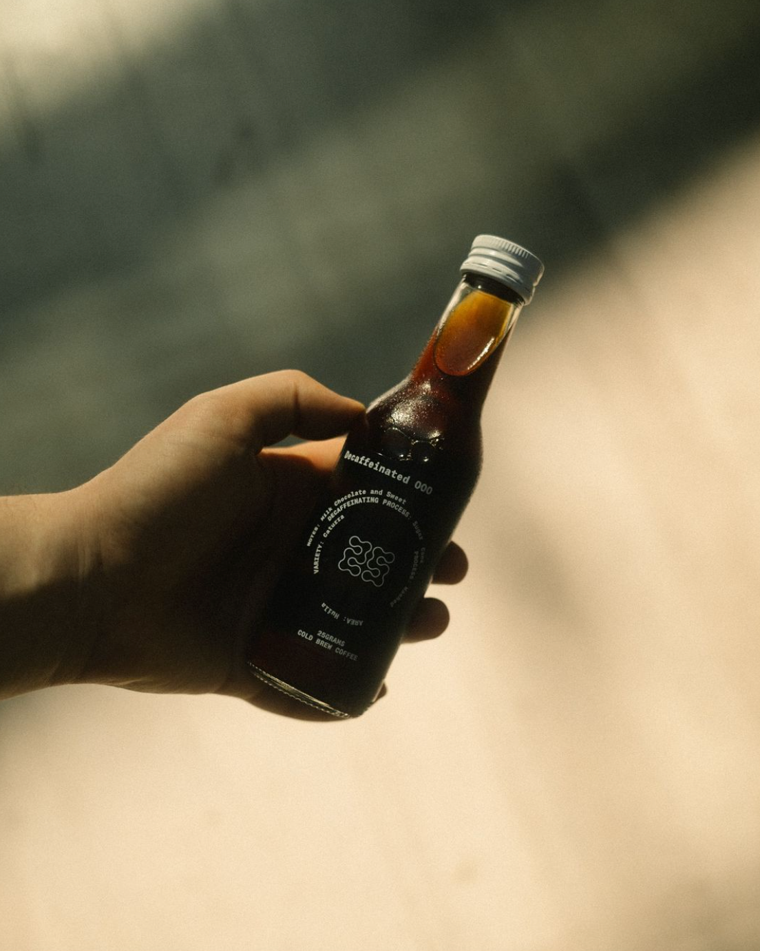 Flasche einkoffeinierter Cold Brew in Hand