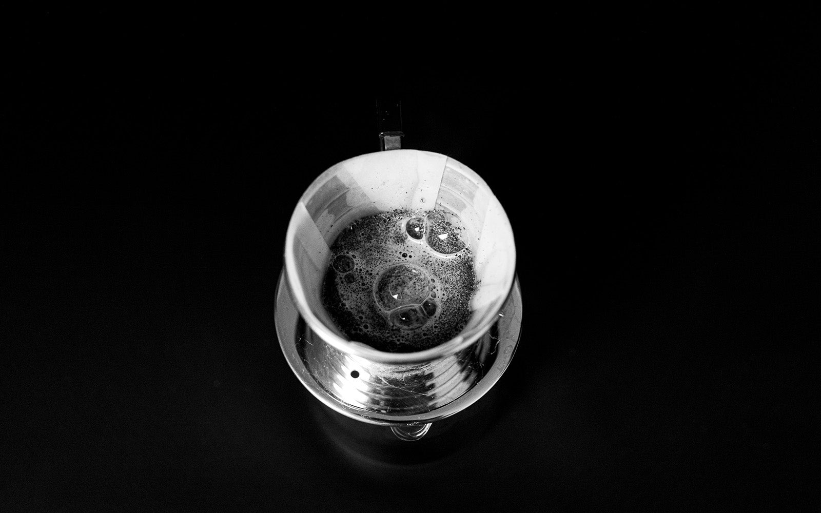 Handfitler von oben, frisch aufgegossener Kaffee wirft Luftblasen