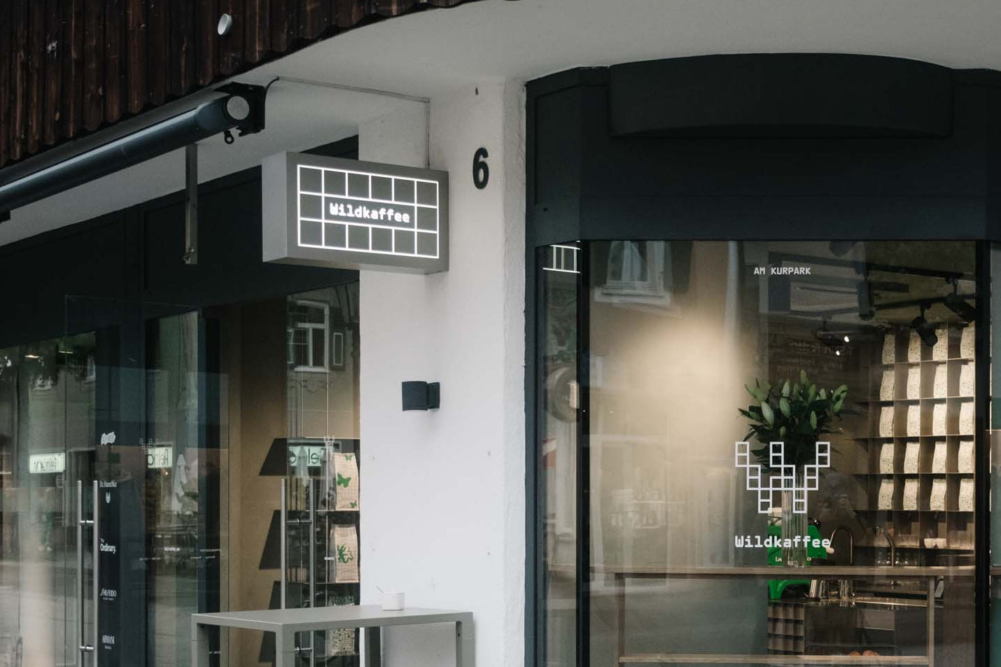 Außenansicht Wildkaffee am Kurpark mit Leuchtschild, Tischen und Stühlen