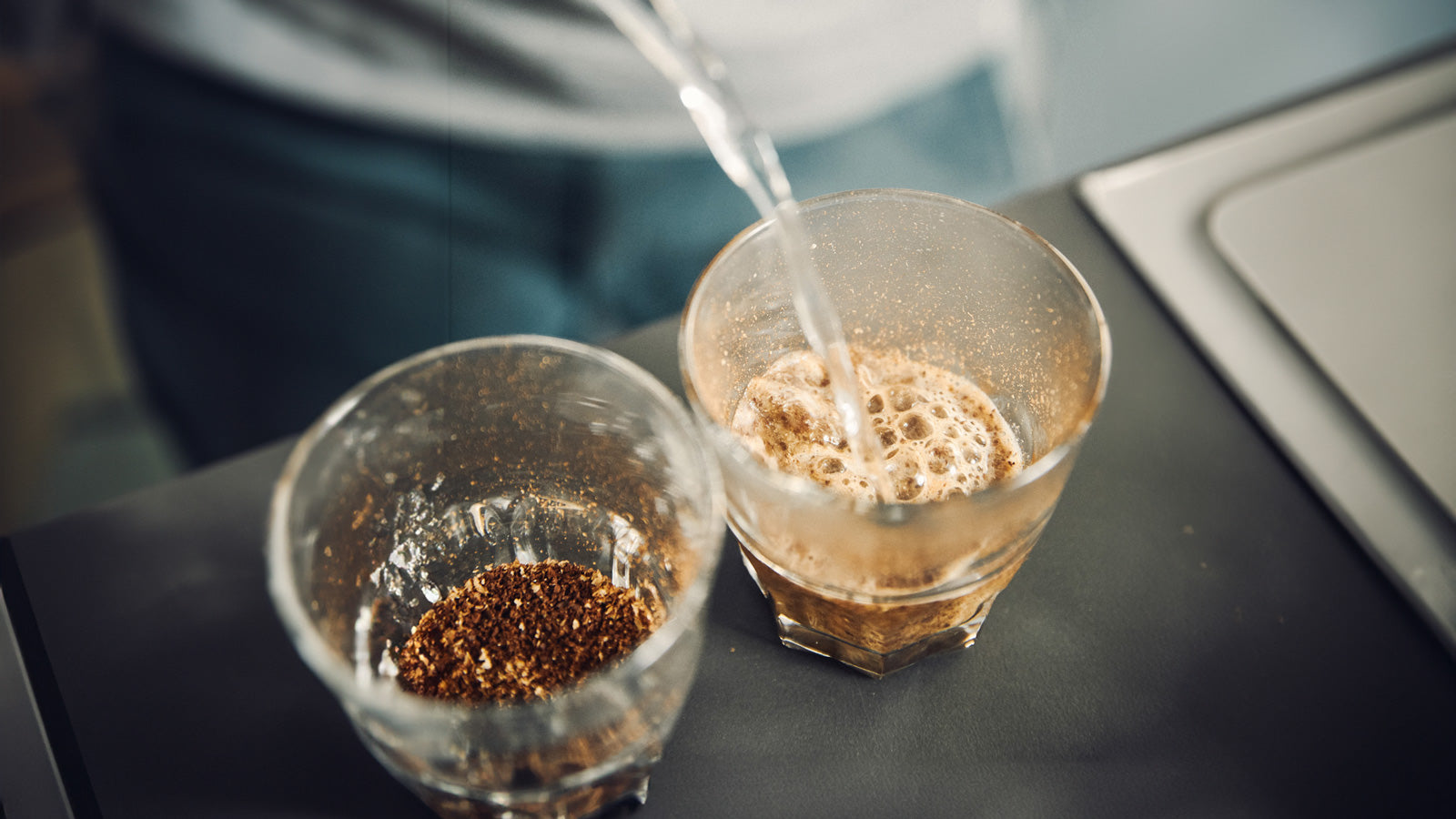 zwei Gläser mit Kaffeepulver, Wasser wird aufgegossen