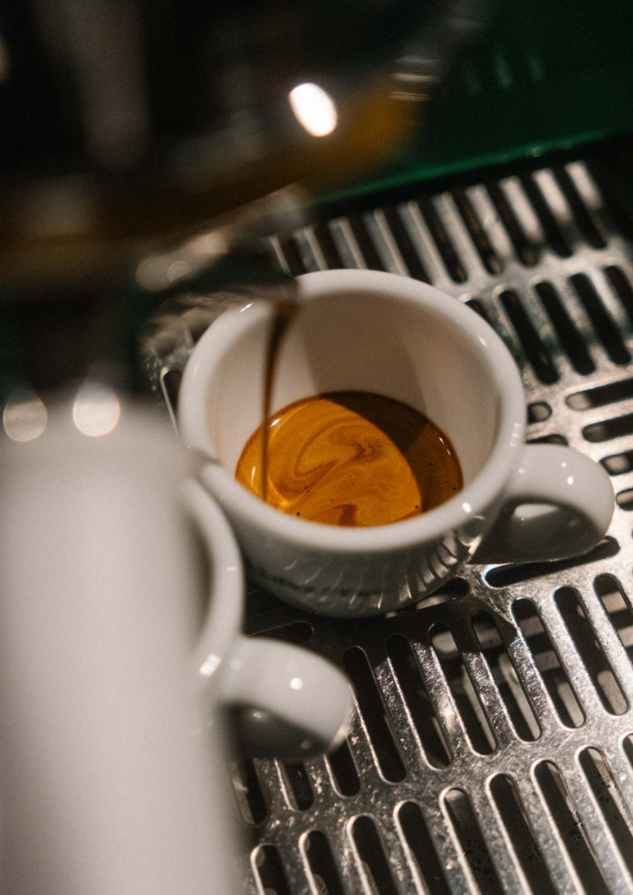 Espresso läuft aus Maschine in Tasse von schräg oben gesehen