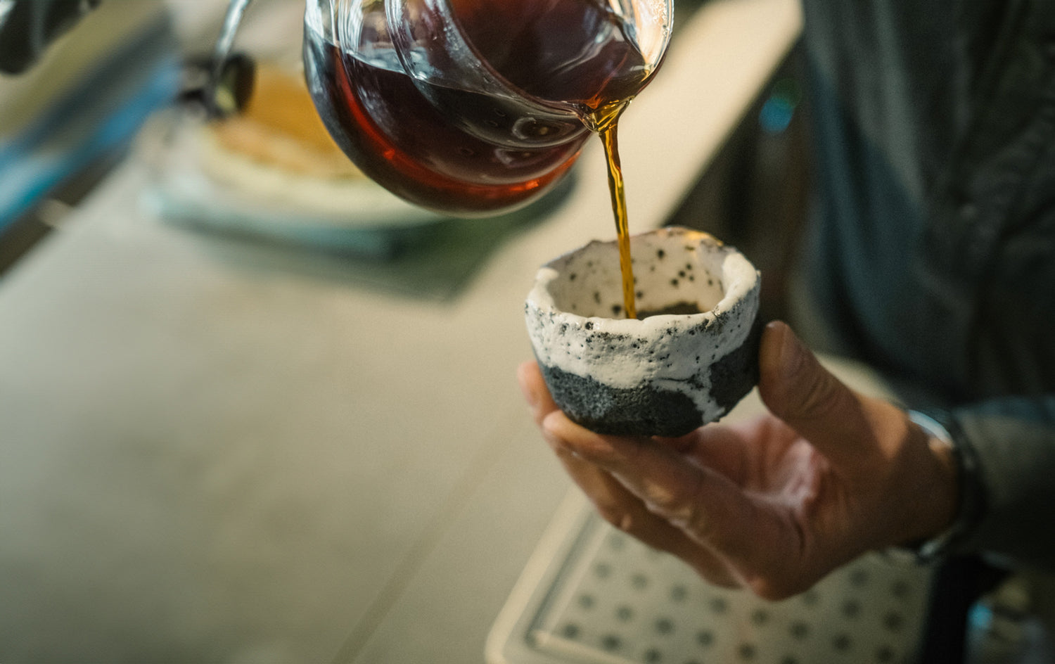 Kaffee für Einstieg Hand hält Tontasse und gießt Kaffee ein