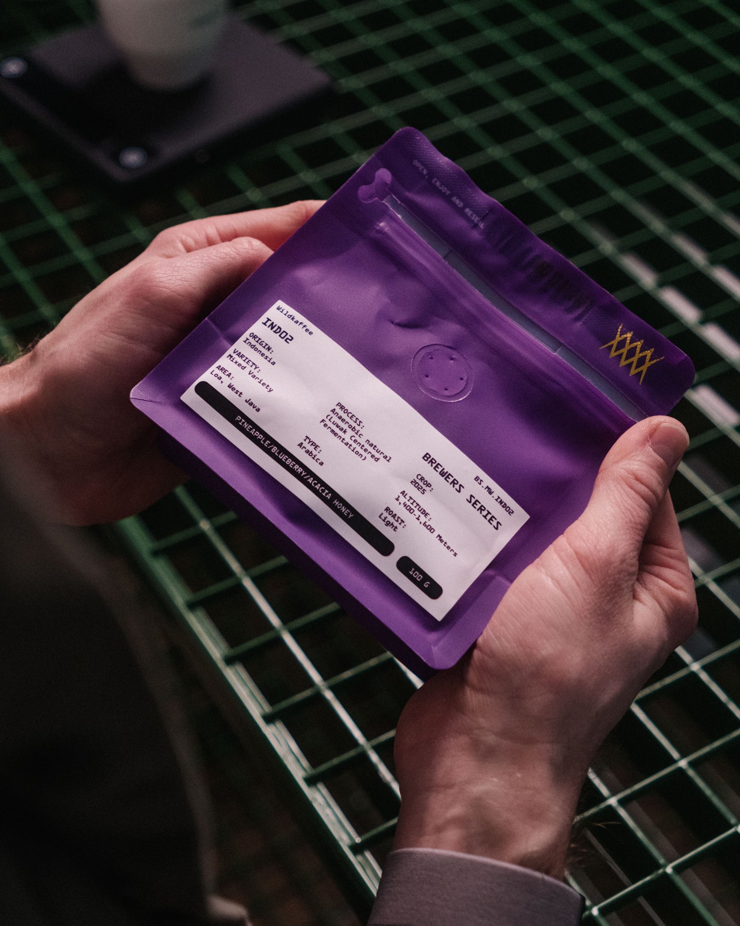 Hände halten lila Kaffeepackung mit weißem Etikett